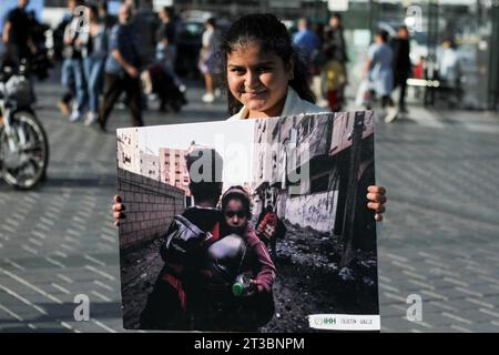 Istanbul, Eminonu, Turchia. 22 ottobre 2023. Un manifestante tiene un cartello che mostra un uomo che aiuta una bambina durante l'attentato a Gaza durante la manifestazione. Le donne hanno organizzato una protesta sit-in, in solidarietà con Gaza nella zona turistica di Eminonu a Istanbul. Sono stati presentati opuscoli di sensibilizzazione sugli eventi attuali a Gaza e sono state esposte foto della città e degli eventi che si sono svolti lì. (Immagine di credito: © Muhmmad al-Najjar/SOPA Images via ZUMA Press Wire) SOLO PER USO EDITORIALE! Non per USO commerciale! Foto Stock