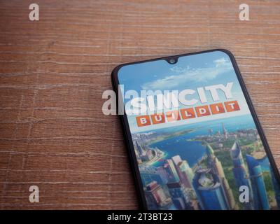 LOD, Israele - 16 luglio 2023: Schermata di avvio dell'app SimCity BuildIt sullo smartphone su sfondo ligneo. Vista dall'alto con spazio per la copia. Foto Stock