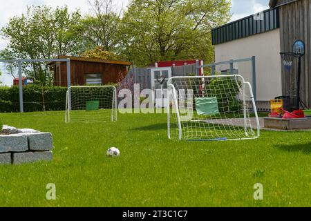 Nel cortile di una casa sull'erba verde c'è un gol e una palla per giocare a calcio. Tempo libero. Foto Stock
