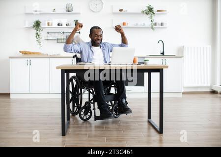 L'utilizzatore africano di sedia a rotelle celebra il successo alzando le mani Foto Stock