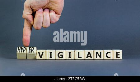 Simbolo di vigilanza o ipervigilanza. Parole concettuali Vigilance Hypervigilance su blocchi di legno. Splendido sfondo grigio. Mano psicologa. Psicologia Foto Stock
