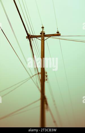 Palo e linee elettriche contro il cielo verde chiaro Foto Stock