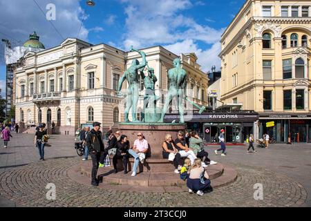 Persone sedute accanto alla statua di Three Smiths in una soleggiata giornata autunnale a Helsinki, Finlandia Foto Stock