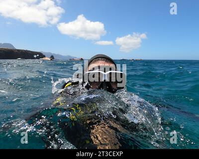 Una subacquea prende un divertente selfie mentre si tuffa in acqua con metà testa sommersa. Concetto di sport acquatici Foto Stock