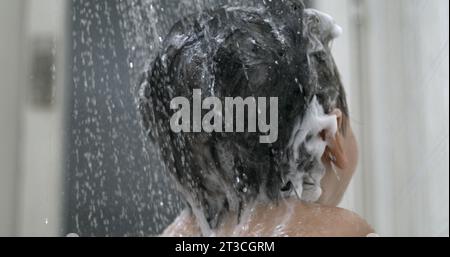 L'acqua viene versata nello shampoo per lavare i capelli del bambino con una routine super slow motion e bagnata. Doccia per i genitori con soffione per bambini Foto Stock