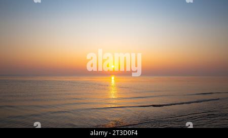 tramonto sul mare con onde lisce e dolci e riflessi nell'acqua Foto Stock