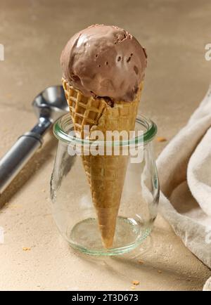 primo piano del gelato al cioccolato e alla banana fatto in casa nel cono dei waffle su sfondo beige Foto Stock