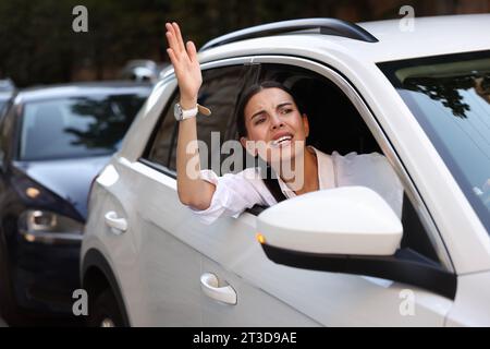 Autista arrabbiato che urla contro qualcuno dall'auto in un ingorgo stradale Foto Stock