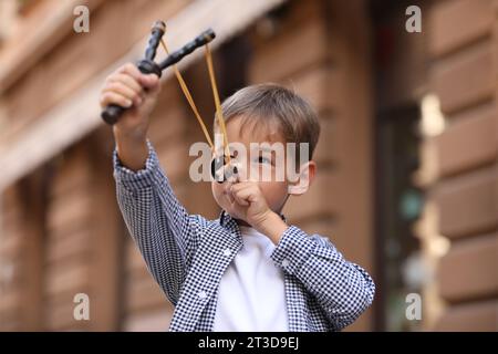 Bambino che gioca con la fionda all'aperto in città Foto Stock