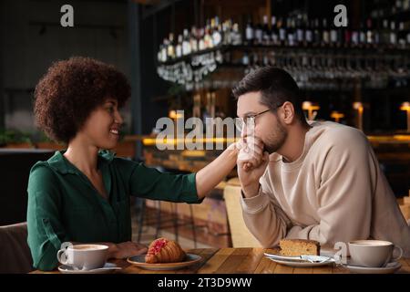 Relazioni internazionali. Bell'uomo che baciava la mano della sua ragazza al bar Foto Stock