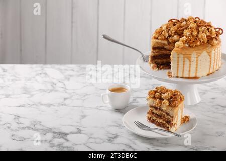 Gocciolatoio al caramello decorato con popcorn e pretzel serviti su un tavolo in marmo bianco, spazio per il testo Foto Stock