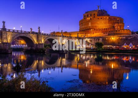 Castel Sant'Angelo e Ponte Sant'Angelo si riflettono nel fiume Tevere al tramonto con un cielo dalle tonalità lilla su Roma. Foto Stock