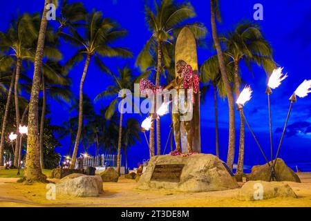 La statua della legena da surf Duke Kahanamoku brilla contro il cielo blu profondo sulla spiaggia di Waikiki, Honolulu, Hawaii. Foto Stock