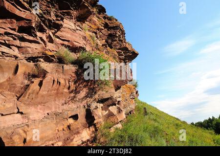 Formazioni di pietra arenaria stratificata con frammenti di erba e cespugli sulla cima di un'alta collina. Catene montuose Chests, Khakassia, Siberia, Russia. Foto Stock