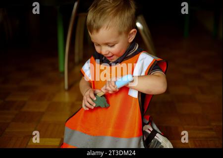 Piccolo bambino vestito da muratore che gioca a casa Foto Stock