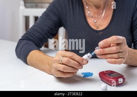 la donna sta preparando le lamelle di sangue per misurare il livello di zucchero nel sangue. Orizzontalmente. Foto Stock