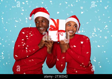 Coniugi neri in posa con regalo di Natale sullo sfondo blu Foto Stock