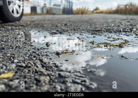 Pozzanghera con riflessi del cielo sulla strada ghiaiosa Foto Stock