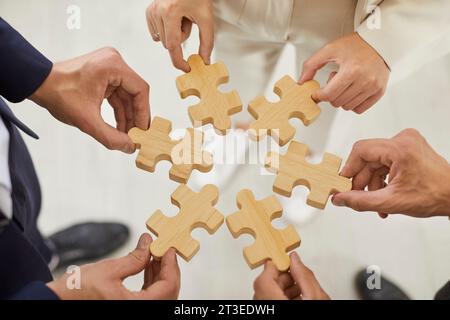 Vista dall'alto mani tagliate di un gruppo di uomini d'affari che assemblano puzzle di legno. Foto Stock