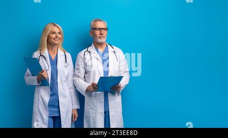 Medici anziani sorridenti e donne che fingono in uniforme Foto Stock