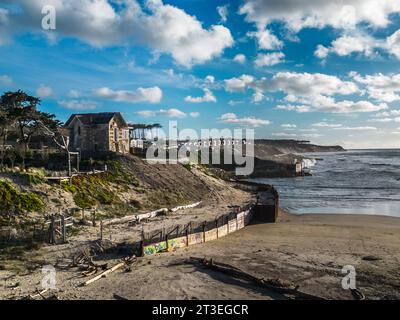 Soulac-sur-Mer (Francia centro-occidentale): Controllo dell’erosione costiera sulla spiaggia “plage de l’Amelie”, riprap, picco roccioso, diga protettiva e onde in wi Foto Stock