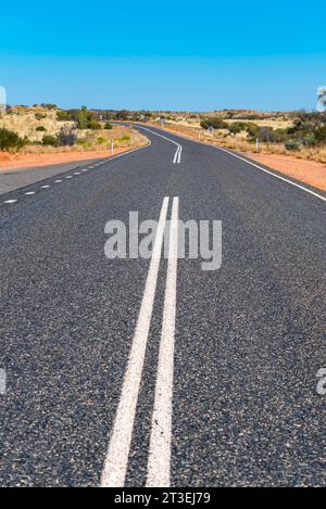 Un lungo tratto rettilineo della Lasseter Highway tra Kings Canyon e Uluru nel territorio del Nord dell'Australia Foto Stock