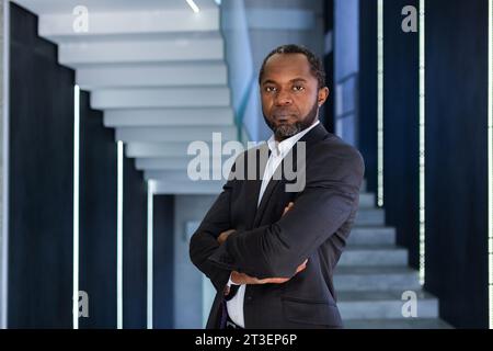 Ritratto di un uomo d'affari serio e sicuro in ufficio con le braccia incrociate, afroamericano che sembra concentrato e penoso davanti alla fotocamera. Foto Stock