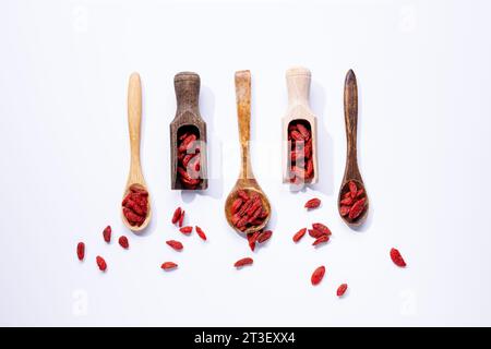 Bacche di goji essiccate su cucchiai di legno isolati su sfondo bianco. Foto Stock