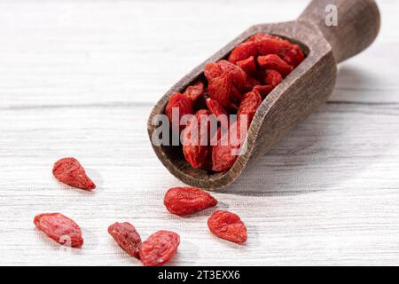 Bacche di goji secche con cucchiaio di legno su sfondo bianco. Foto Stock