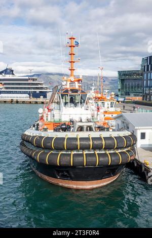 Atlas Ocean Voyages World Traveller, piccola nave da crociera in stile yacht a Port Reykjavik, Islanda, con rimorchiatori fuori dall'Harpa Centre Foto Stock