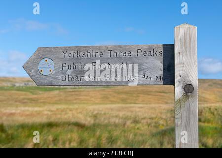 Un cartello di legno per il sentiero pubblico Yorkshire Three Peaks che indica i binari di Bleamoor Foto Stock