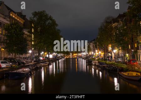 Paesi Bassi. Notte d'estate sul canale di Amsterdam. Lanterne e auto parcheggiate sui terrapieni. Barche ormeggiate lungo le rive del canale Foto Stock