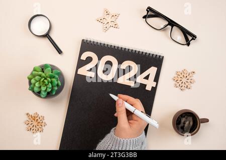 Il nuovo anno punta al 2024. Elenco attività. Notebook vuoto alla scrivania con decorazioni natalizie. Vista dall'alto. Creazione piano, risoluzione. Nuova vita, inizio, inizio Foto Stock