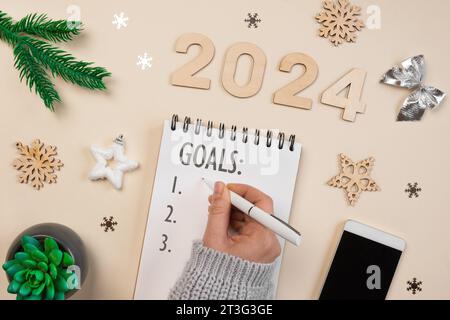 Il nuovo anno punta al 2024. Elenco attività. Notebook vuoto alla scrivania con decorazioni natalizie. Vista dall'alto. Creazione piano, risoluzione. Nuova vita, inizio, inizio Foto Stock