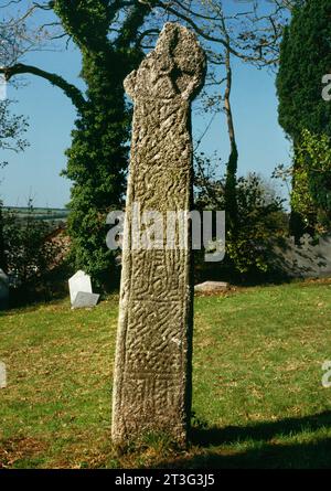 E faccia di una croce sassone con testa a rotellina N della chiesa di Lanivet, Cornovaglia, Inghilterra, Regno Unito, con un uomo con una "coda" sull'asta di granito . Foto Stock