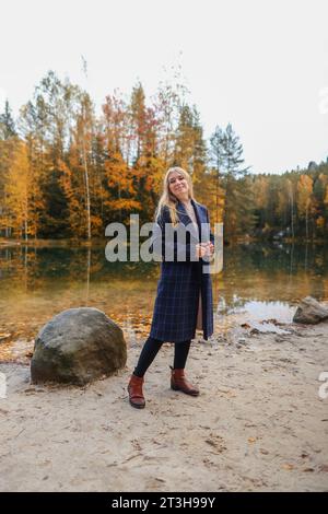 donna con berretto vicino al lago in autunno Foto Stock