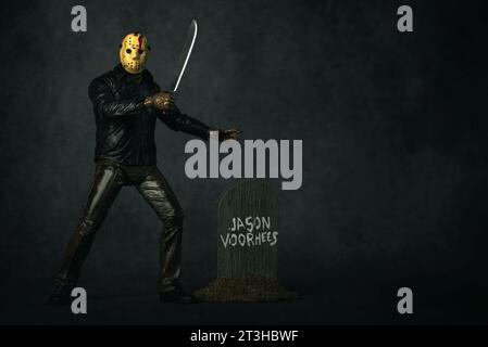 Figura di Jason Voorhees con machete protagonista della serie di film venerdì 13 su sfondo grigio. Editoriale illustrativo Foto Stock