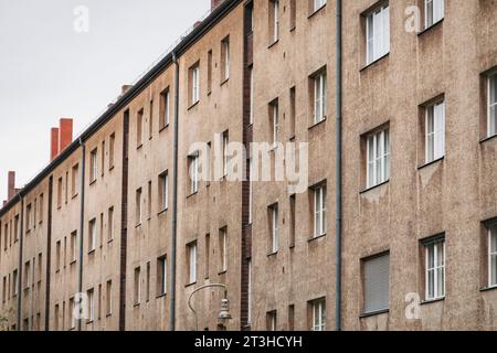 File di finestre su un lungo condominio grigio a Berlino, Germania Foto Stock