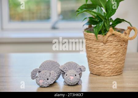 Carini coniglietti lavorati a maglia sul tavolo vicino al vaso da fiori Foto Stock