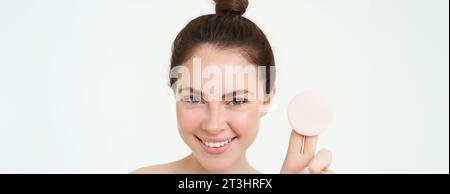 Cura della pelle e benessere. La giovane donna mostra un batuffolo di cotone cosmetico, si toglie il trucco, usando un detergente per il viso e lavandosi il viso con un trattamento per la cura della pelle Foto Stock