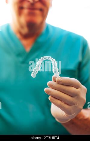 Un medico che tiene in mano un allineatore dentale libero Foto Stock