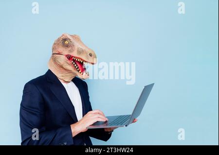 uomo con maschera di dinosauro che usa un notebook Foto Stock