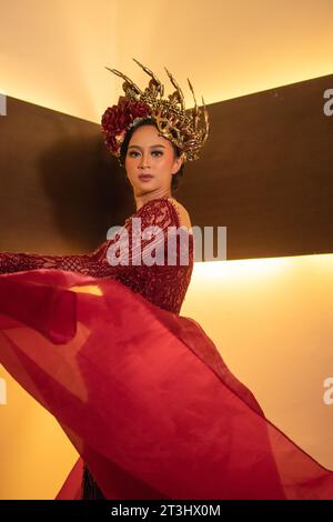 Una bella donna asiatica alza la coda di tessuto rosso indossando un abito da sposa rosso prima della cerimonia di nozze Foto Stock
