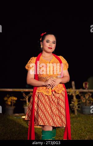 Donna sundanese che indossa un abito corto e un tradizionale abito giallo con sciarpa rossa e trucco dopo lo spettacolo di danza sul palco Foto Stock