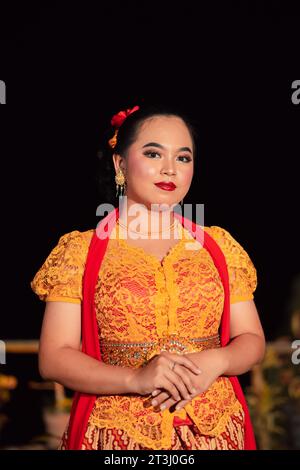 Donna sundanese che indossa un abito corto e un tradizionale abito giallo con sciarpa rossa e trucco dopo lo spettacolo di danza sul palco Foto Stock