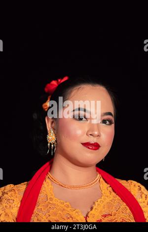 Donna sundanese che indossa un abito corto e un tradizionale abito giallo con sciarpa rossa e trucco dopo lo spettacolo di danza sul palco Foto Stock