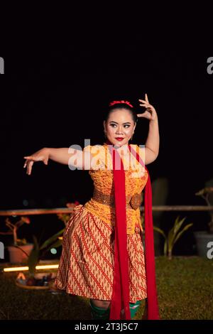 Donna sundanese con un viso esotico che indossa un vestito giallo e una sciarpa rossa durante una mostra di danza al festival Foto Stock