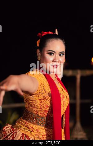 Donna sundanese con un viso esotico che indossa un vestito giallo e una sciarpa rossa durante una mostra di danza al festival Foto Stock