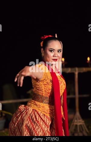 Donna sundanese con un viso esotico che indossa un vestito giallo e una sciarpa rossa durante una mostra di danza al festival Foto Stock