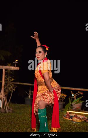 Donna asiatica che esegue una danza tradizionale chiamata jaipong in Indonesia con un vestito giallo e una sciarpa rossa al festival di danza Foto Stock